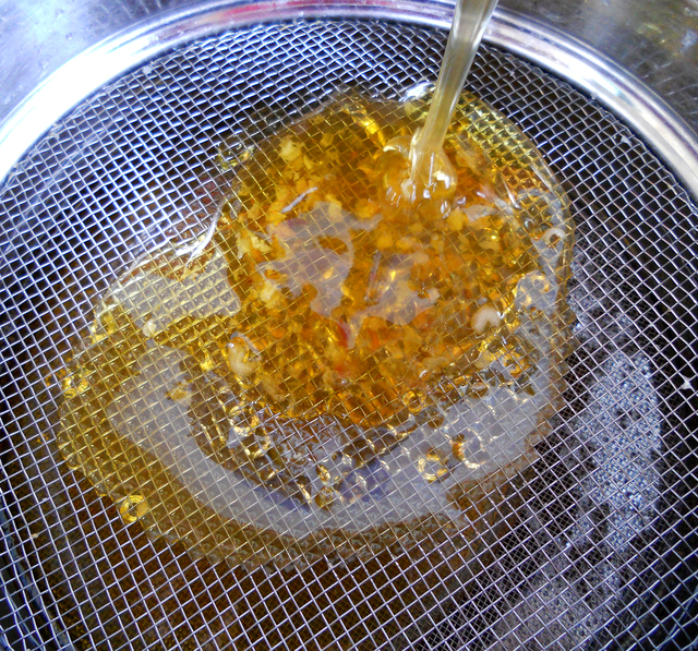 Beekeeper showcasing the process of straining honey.