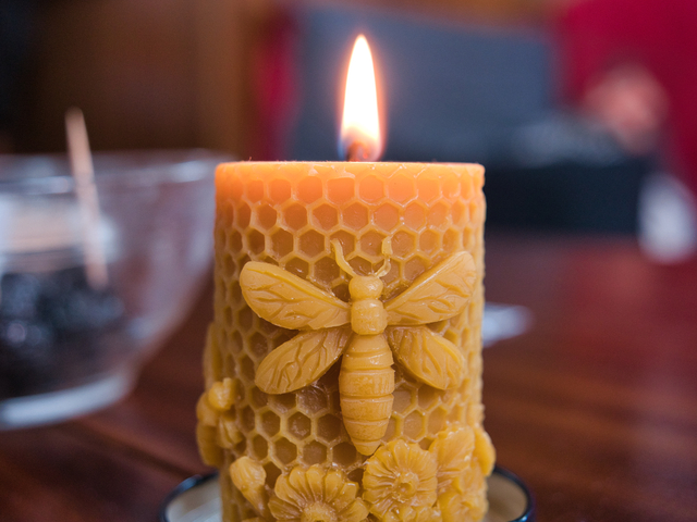 Burning candle with bee sculpture fixed on it.